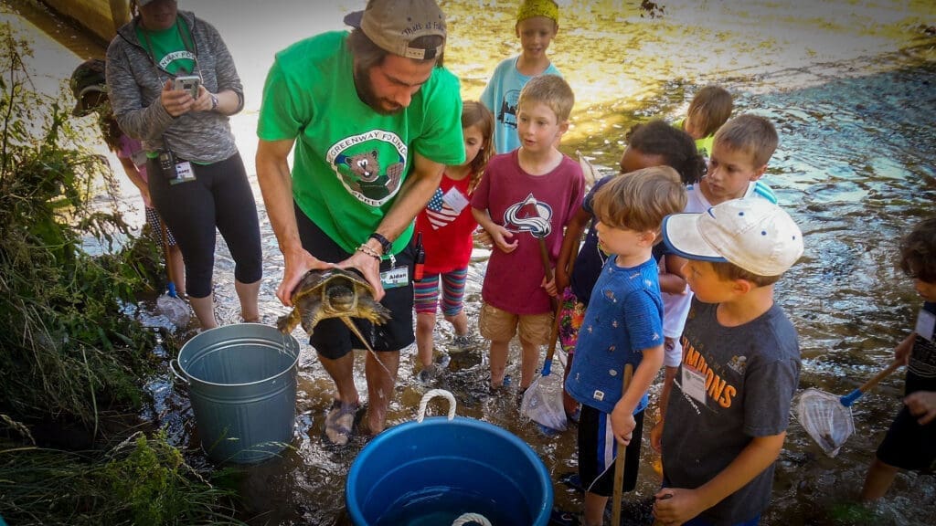 A SPREE Staff Member shows a river turtle to interested campers.