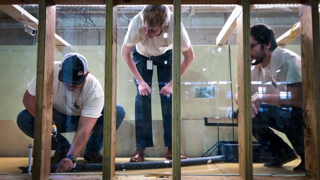 Clean Water Challenge team works to install a prototype device in a river flow simulator.